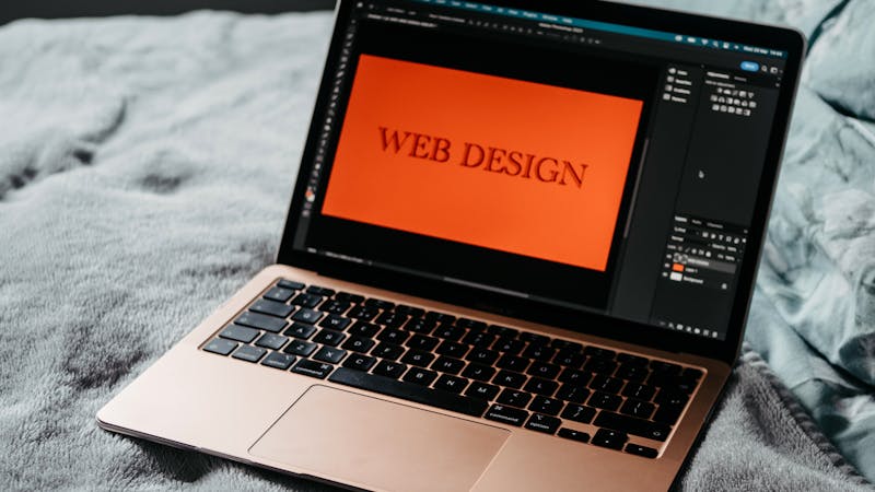 Laptop open on a desk showing a styled web design project in progress