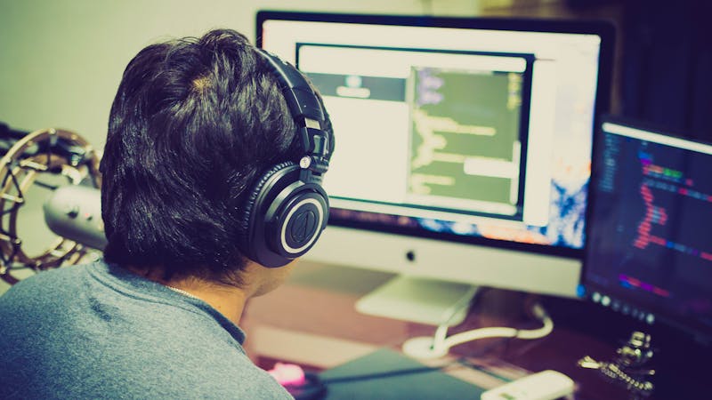 Developer working with technology tools and multiple screens